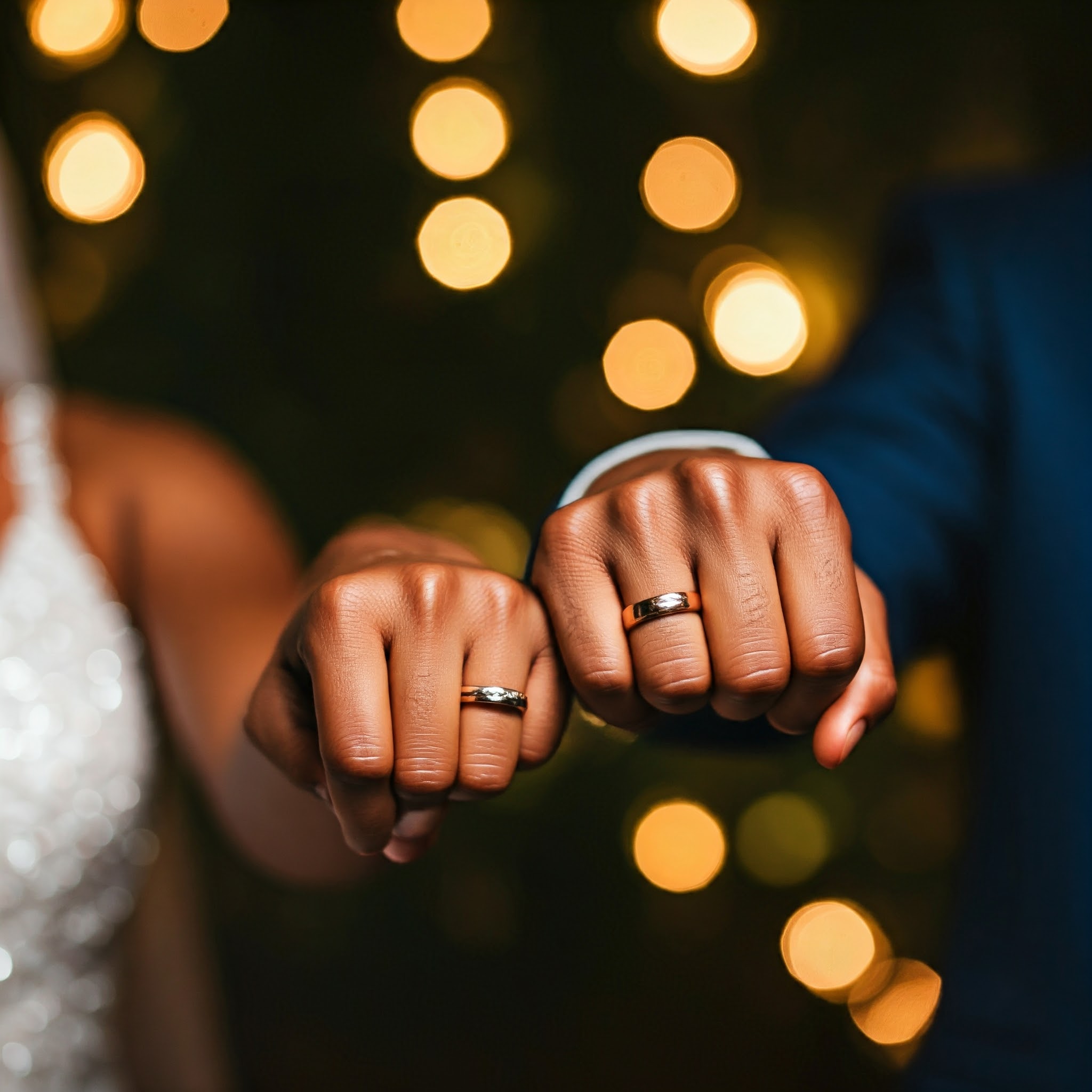 Casal apontando as mãos a frente exibindo alianças de casamento.