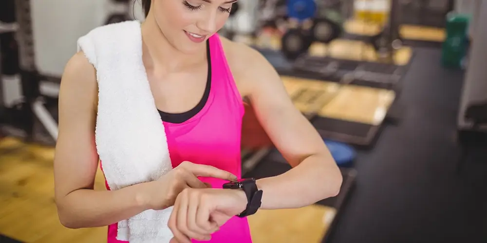 mulher na academia olhando para a tela de seu smartwatch