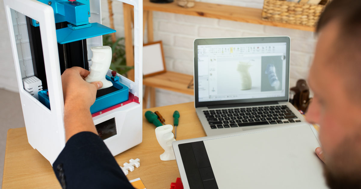  homem compara uma recém peça em 3d impressa com o arquivo no computador