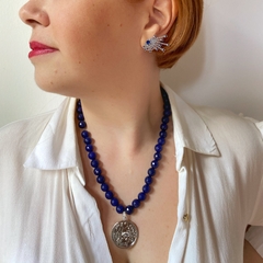 detalhe na modelo da combinação de brinco zircônias azuis e colar em jade azul e pingente amuleto banhado a ródio branco