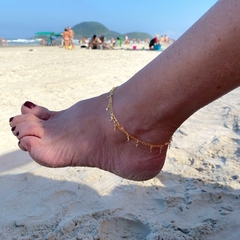 detalhe no tornozelo da tornozeleira semijoia dupla correntinha com pingentes de luas e estrelas banhado a ouro 18k